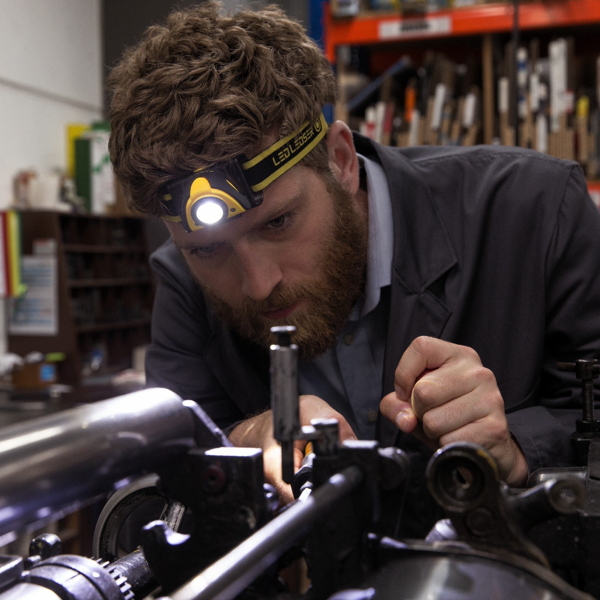 Ledlenser iSEO3 Battery Operated Headlamp worn by a bearded man in a workshop lighting a component on a machine