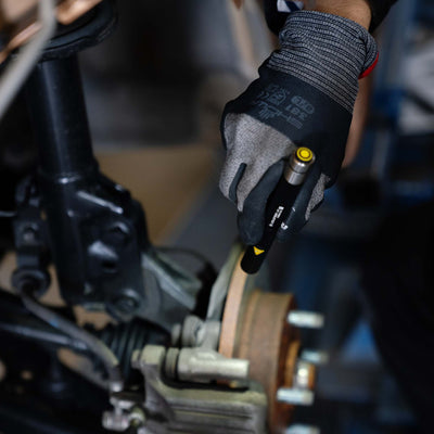 Ledlenser i4 Torch held in gloved hand above industrial machinery with yellow activation button visible