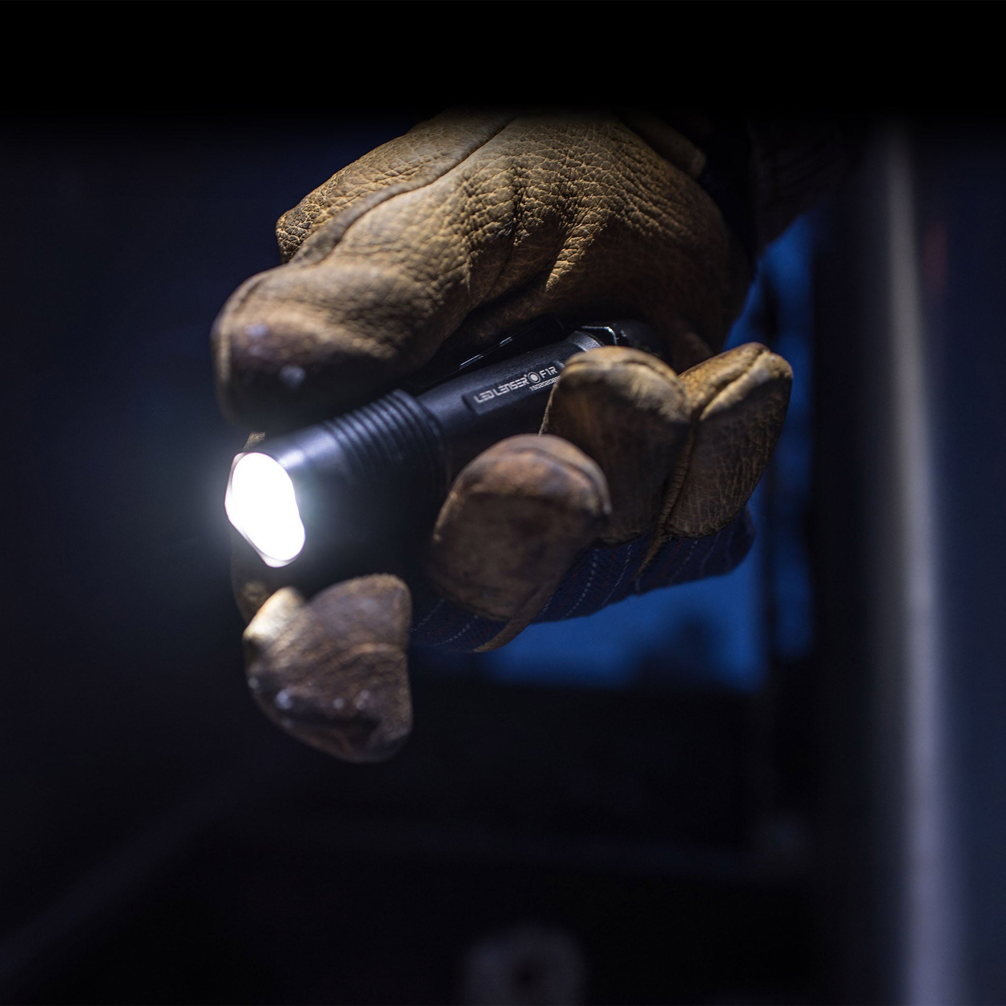 F1R Torch held in a gloved hand emitting light in a dark setting