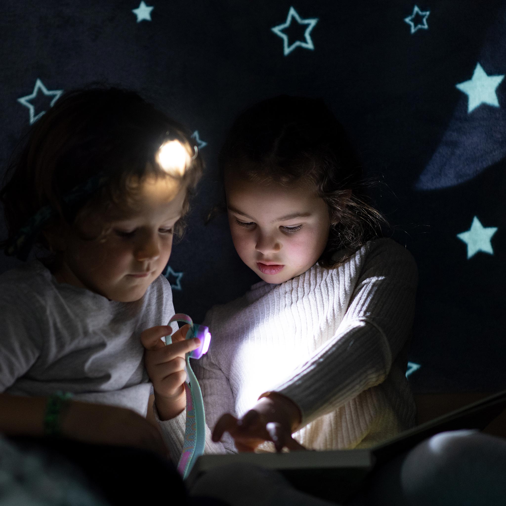 Kidled4R Headlamp worn by a child; two children reading a book in low light with the headlamp illuminating the pages