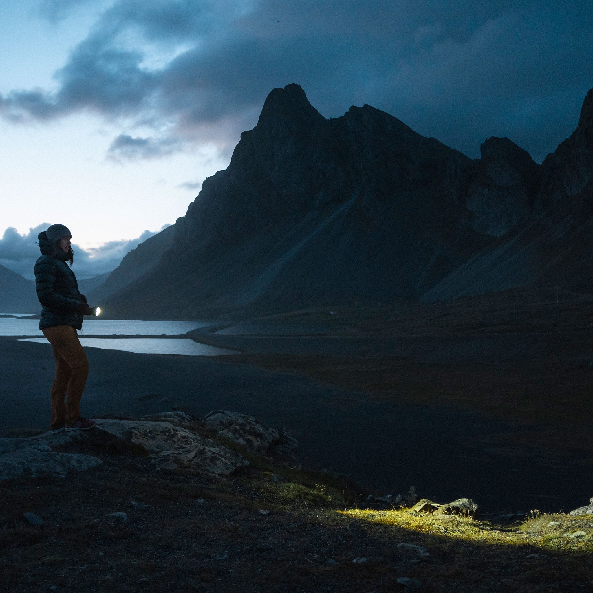 Ledlenser P18R Signature Torch held by a person in an outdoor night scene with mountains in the background