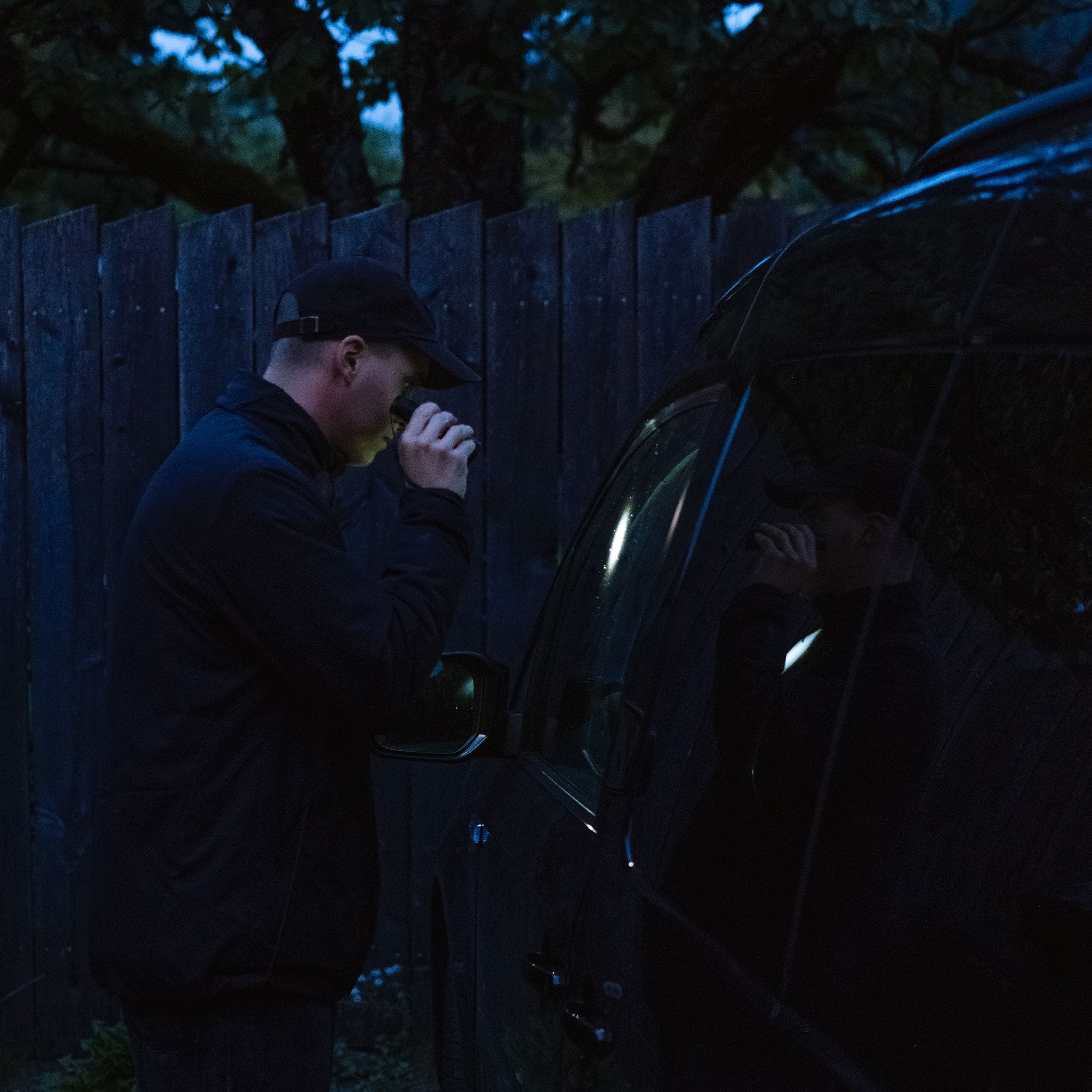 P6 Core Torch held by a person at night beside a dark vehicle blue ambient lighting