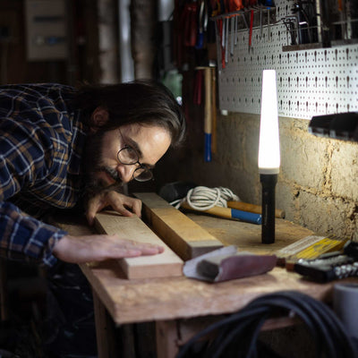 Ledlenser Signal Cone W 42mm product image showing a man at a woodwork bench with a tall lamp on the bench in a workshop