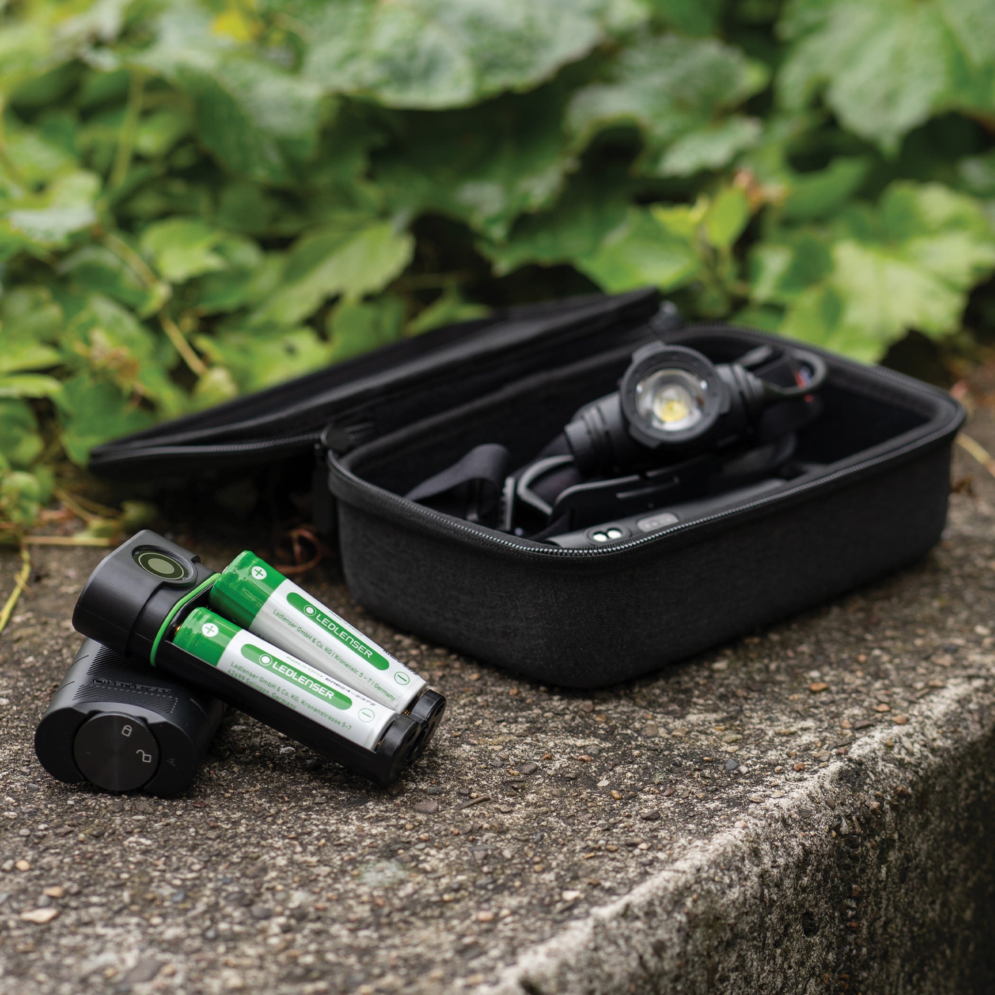 Flex10 Powerbank with two green Ledlenser rechargeable batteries and an accessories case containing a headlamp outdoors