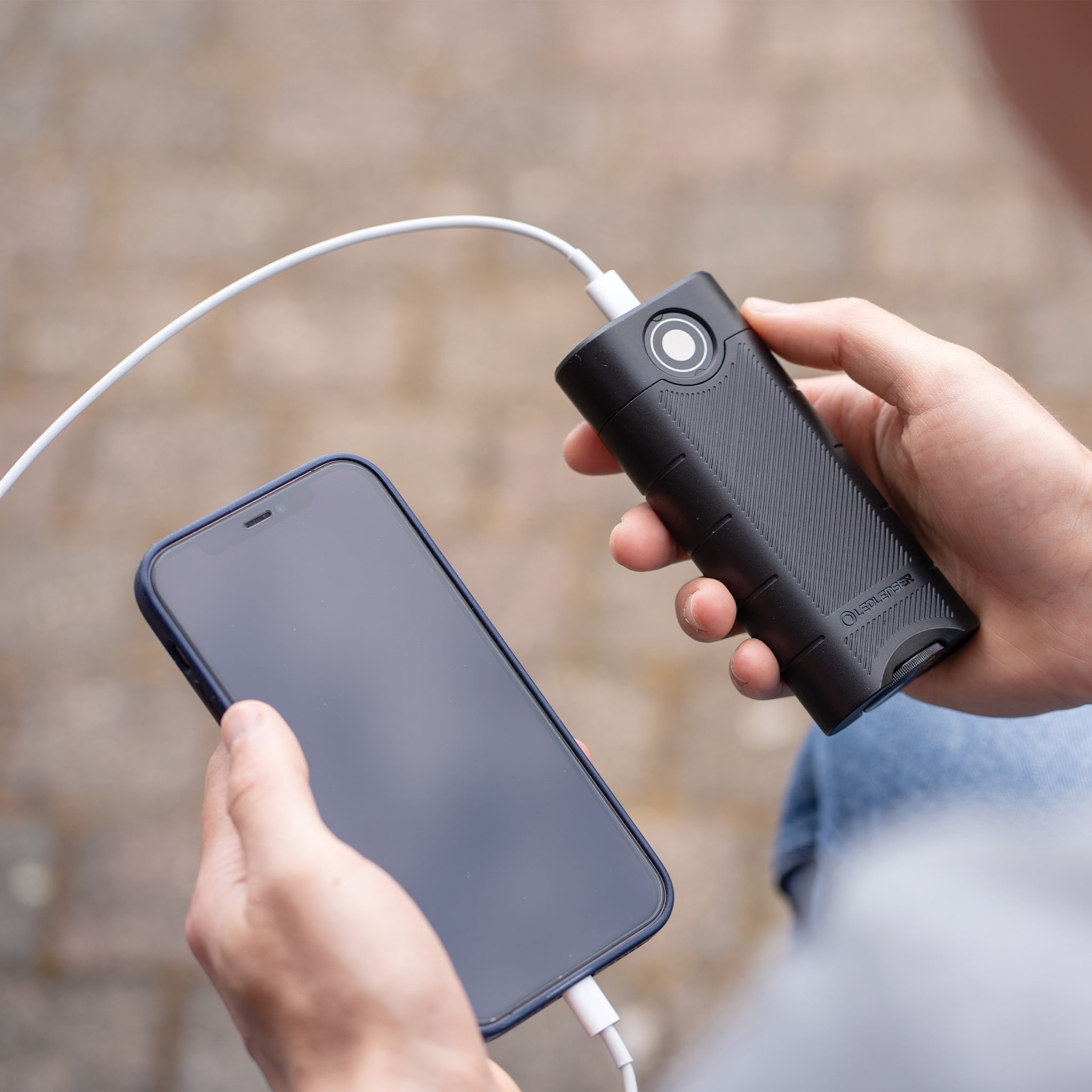 Ledlenser Flex10 Powerbank in black textured finish charging a smartphone with a white charging cable