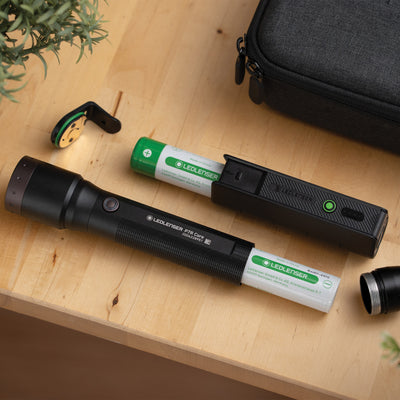 Ledlenser Flex5 Powerbank with detachable charging module and green battery on a wooden surface beside a black carry case