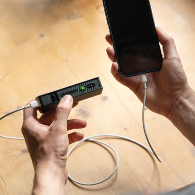 Flex5 Powerbank by Ledlenser being held with a USB C cable charging a smartphone; black rectangular power bank with green status LEDs