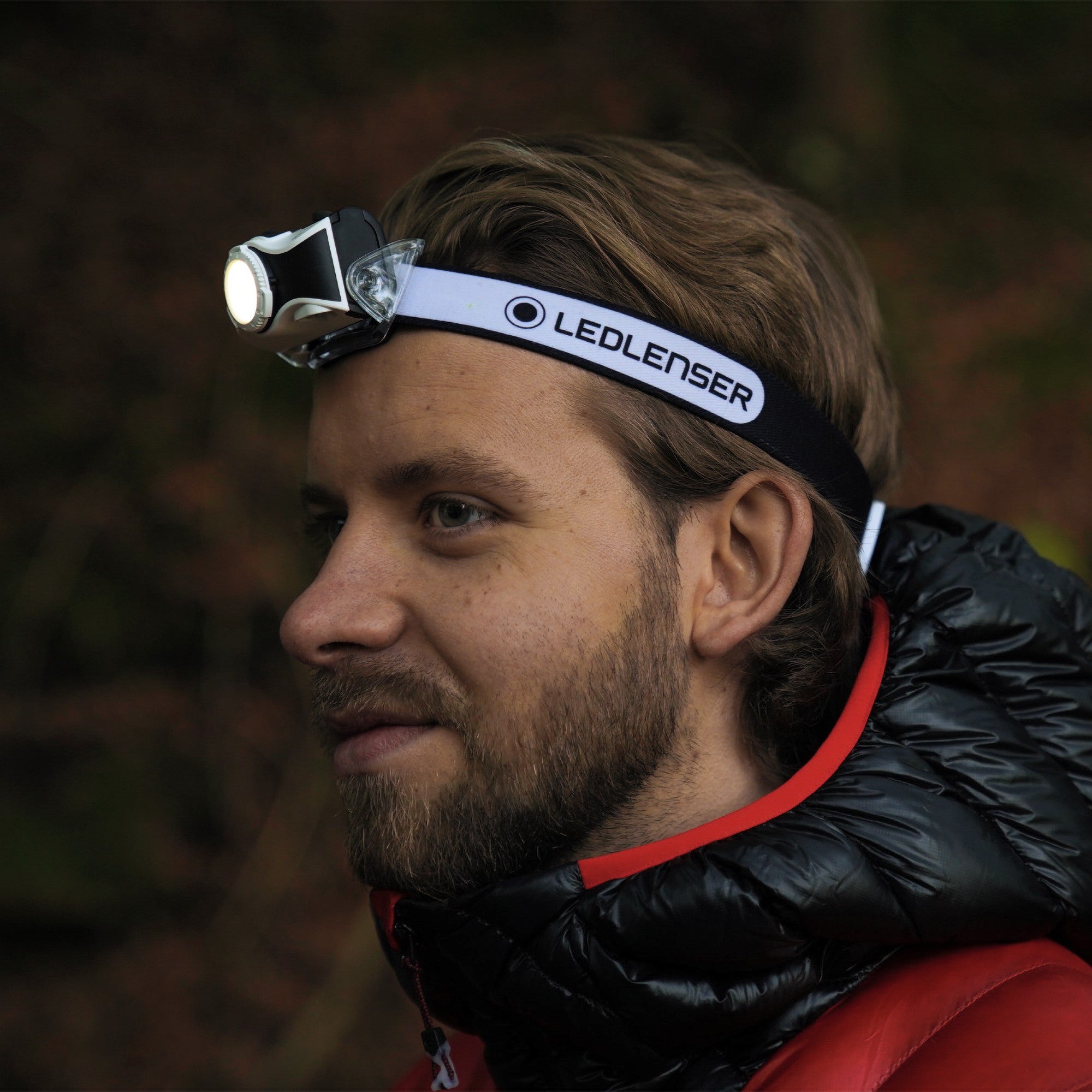 MH7 Green Rechargeable Headlamp worn on a man’s head with a lit lamp black headband with Ledlenser branding