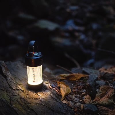 Ledlenser ML4 Warm Light Lantern shown outdoors on rocky ground with a warm beam emitted from its lantern body