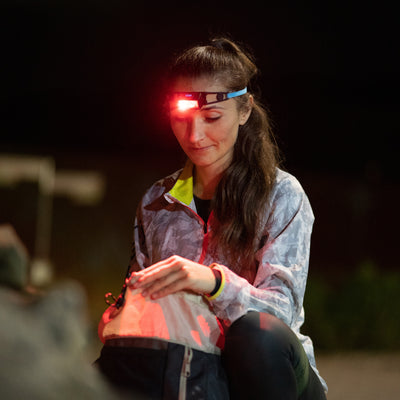NEO1R Headlamp worn by a woman at night with a red beam outdoors head mounted lighting in use