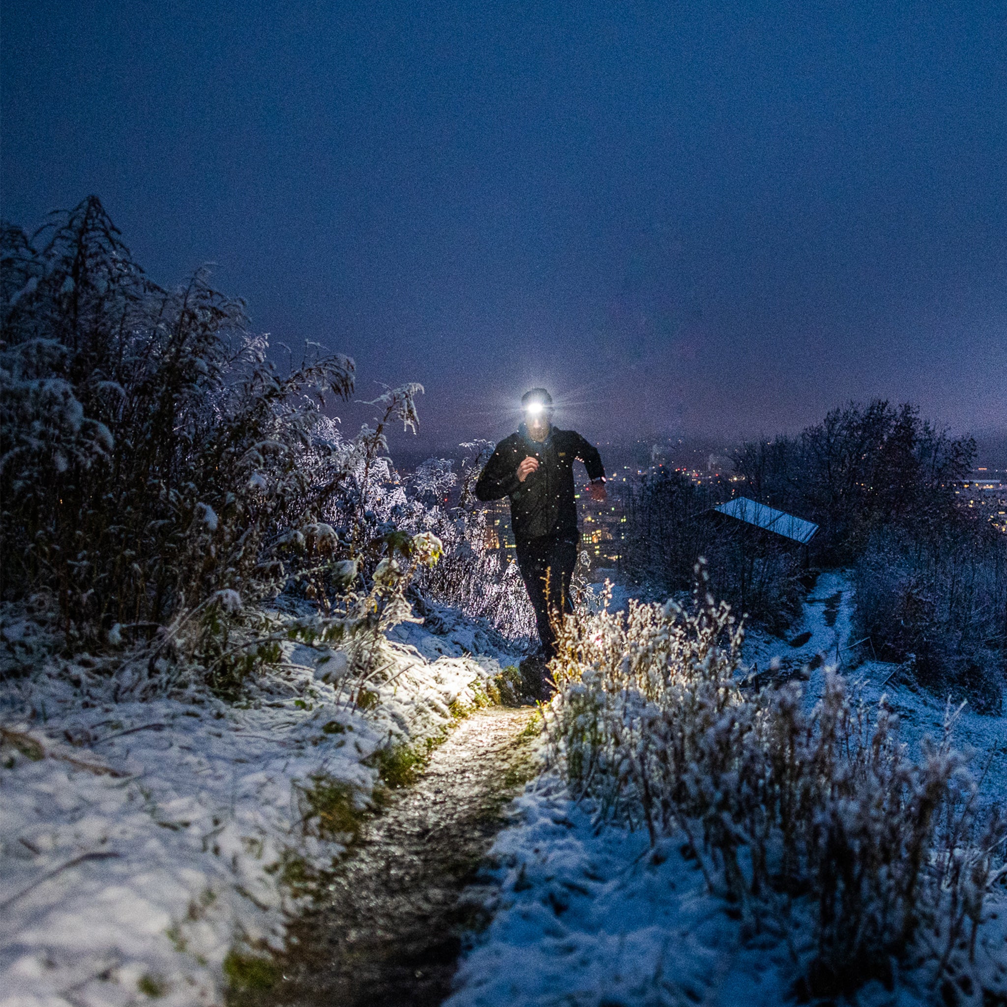 Ledlenser NEO5R Rechargeable Headlamp worn by a runner on a snowy trail at night with illuminated beam