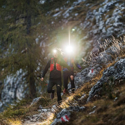 NEO9R Running Headlamp worn by a hiker during night trail run; two people on a rocky slope with bright headlamp beam