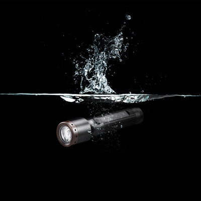 Ledlenser P5R Core Torch submerged in water with splash showing a compact rechargeable flashlight design in a dark background
