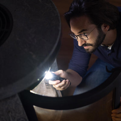 Ledlenser P7R Core torch held in a man's hand angled to illuminate a dark surface during inspection