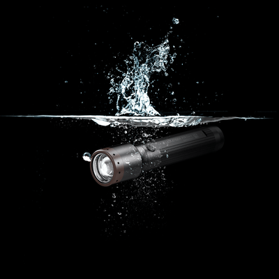 Ledlenser P7R Core Torch submerged in water with splash showing a black cylindrical body and brown bezel