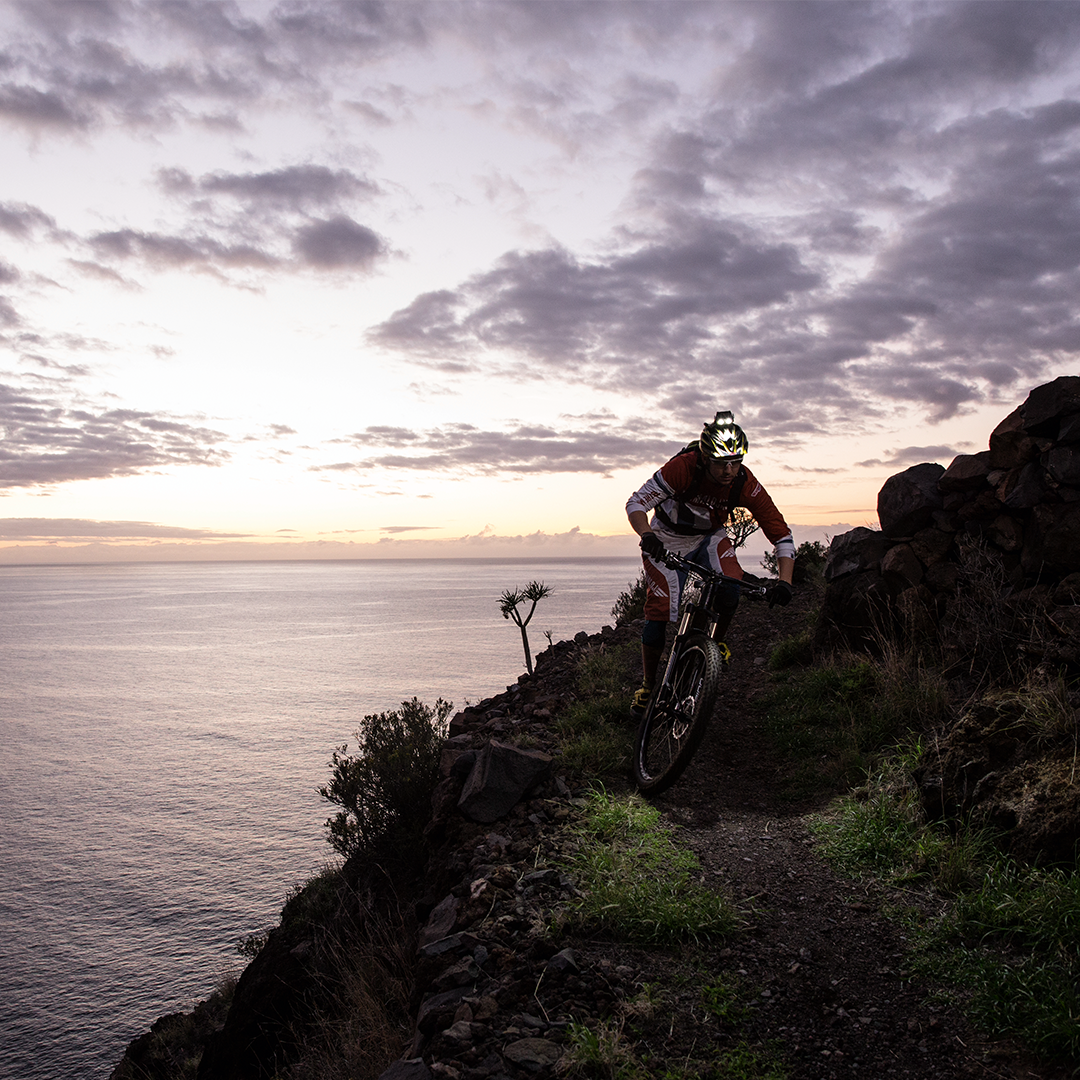 XEO19R Rechargeable Headlamp mounted on a cyclist's helmet during a mountain bike trail at sunset
