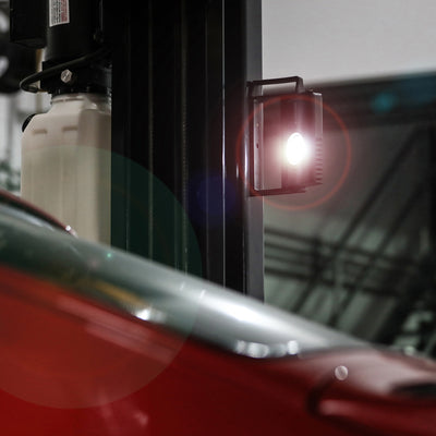 Ledlenser iF4R Spotlight mounted on a vertical rail beside a red vehicle with its beam lit