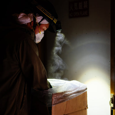 Ledlenser iLH8 Headlamp worn by a worker in a dark room inspecting a cardboard box with illuminated beam